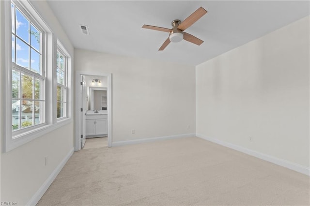 unfurnished room featuring light carpet, plenty of natural light, visible vents, and baseboards