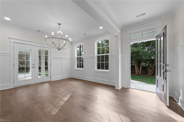 interior space with crown molding, visible vents, a decorative wall, and wood finished floors