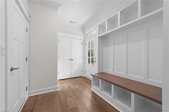 mudroom with baseboards, crown molding, visible vents, and wood finished floors