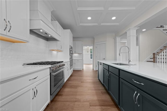 kitchen featuring appliances with stainless steel finishes, white cabinetry, a sink, and custom exhaust hood