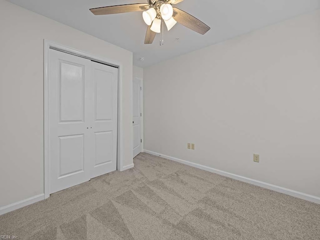 unfurnished bedroom with a closet, baseboards, light colored carpet, and ceiling fan