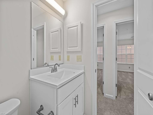 bathroom featuring toilet, vanity, and baseboards