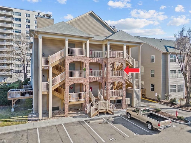 view of building exterior with stairway and uncovered parking