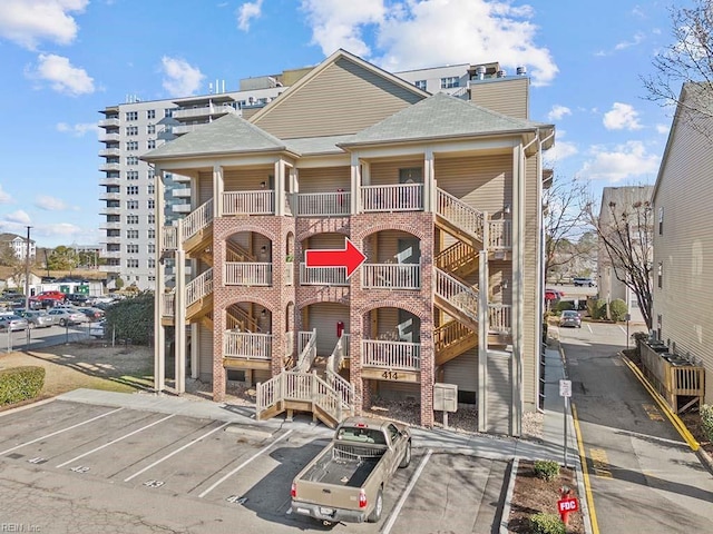 view of property with stairway and uncovered parking