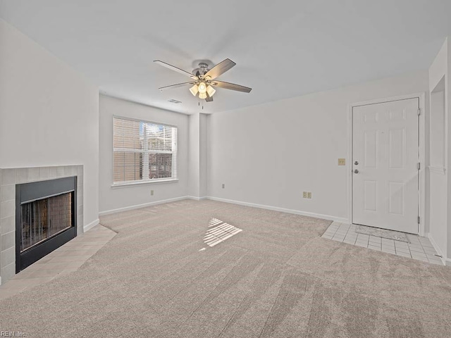 unfurnished living room featuring a ceiling fan, visible vents, baseboards, carpet floors, and a tile fireplace