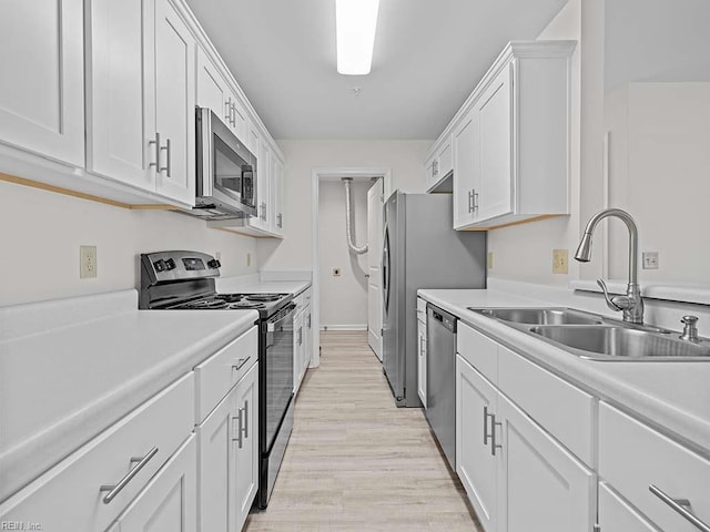 kitchen with white cabinetry, stainless steel appliances, light wood-style floors, and a sink