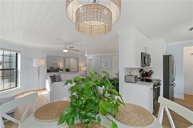 dining room with crown molding, ceiling fan with notable chandelier, and light hardwood / wood-style floors