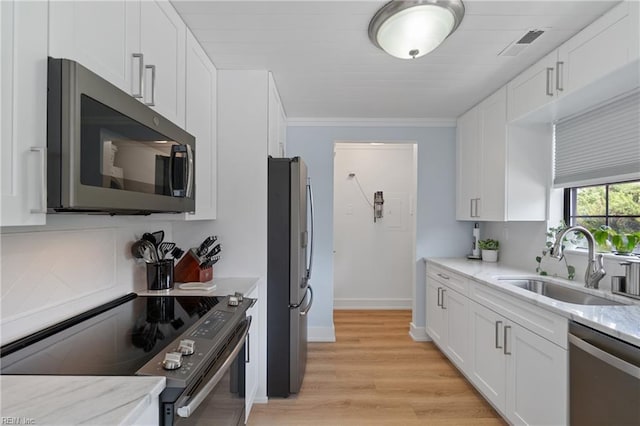 kitchen featuring appliances with stainless steel finishes, sink, white cabinets, and light stone counters