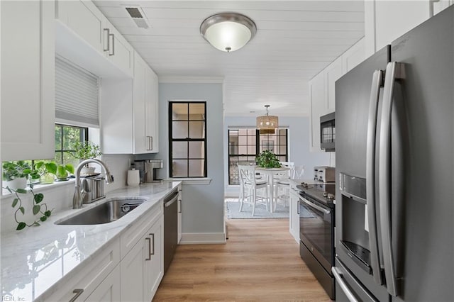 kitchen featuring stainless steel appliances, hanging light fixtures, sink, and white cabinets