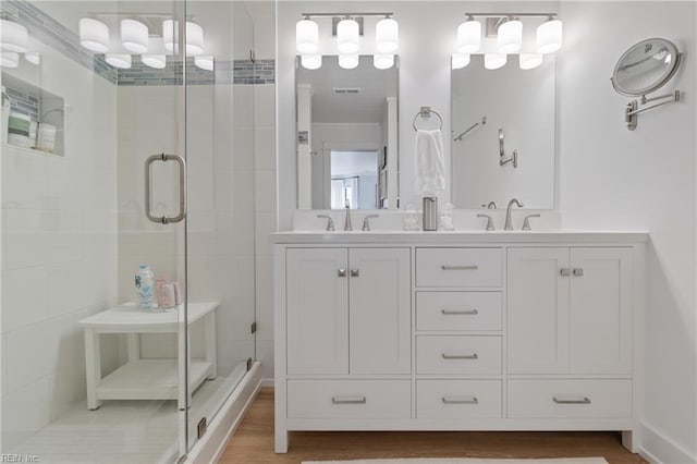 bathroom featuring vanity, wood-type flooring, and a shower with door