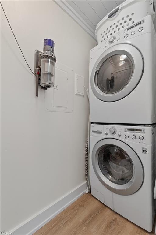 laundry room featuring stacked washer / dryer and light wood-type flooring