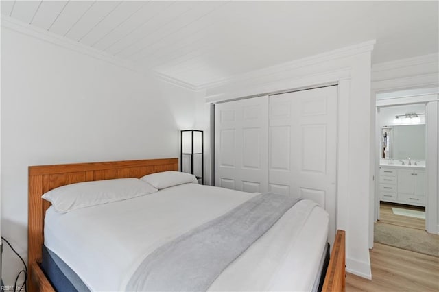 bedroom featuring crown molding, sink, light hardwood / wood-style flooring, and a closet