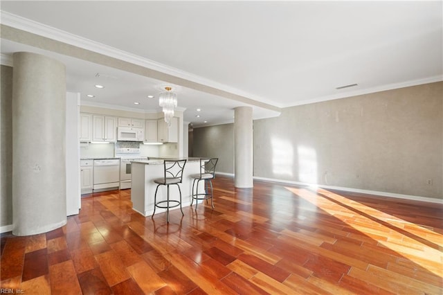 kitchen with white appliances, hardwood / wood-style flooring, white cabinetry, a center island, and a kitchen bar