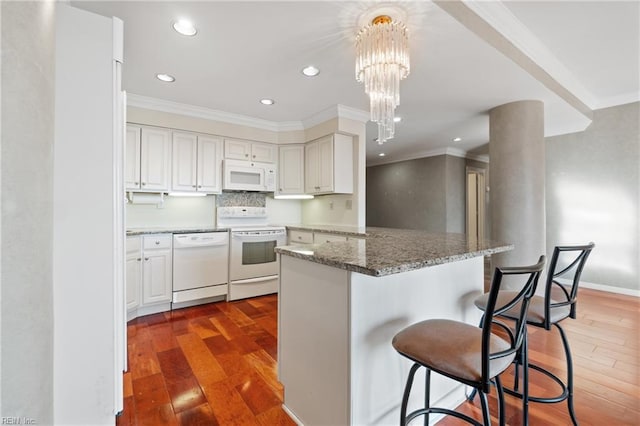 kitchen with pendant lighting, white appliances, wood-type flooring, stone countertops, and kitchen peninsula