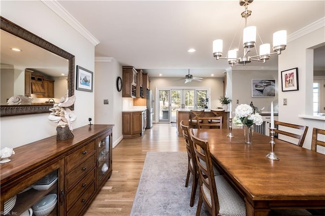 dining room with crown molding, ceiling fan with notable chandelier, and light wood-type flooring