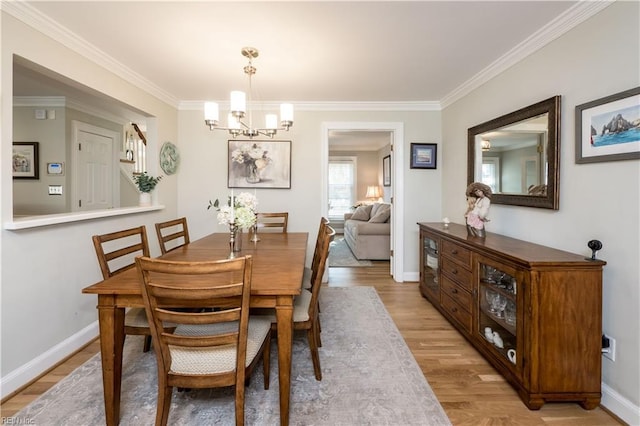 dining area featuring crown molding, a notable chandelier, and light wood-type flooring