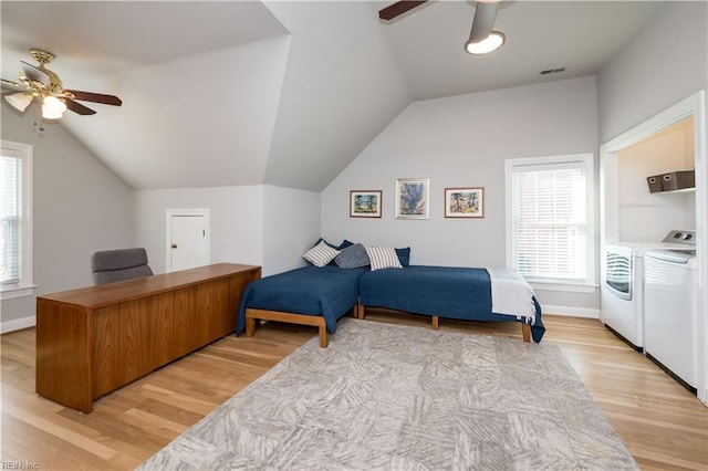 bedroom featuring multiple windows, light hardwood / wood-style flooring, and washing machine and dryer