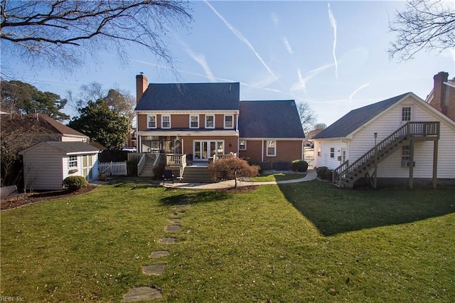 back of property featuring french doors, a storage unit, and a lawn