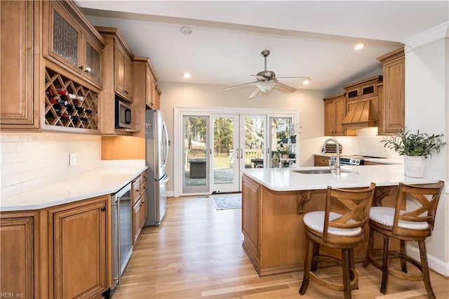 kitchen with sink, premium range hood, stainless steel appliances, kitchen peninsula, and french doors