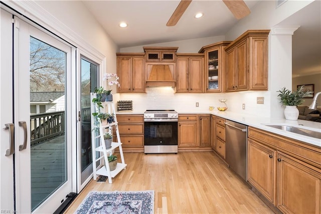 kitchen featuring lofted ceiling, sink, custom exhaust hood, stainless steel appliances, and light hardwood / wood-style flooring