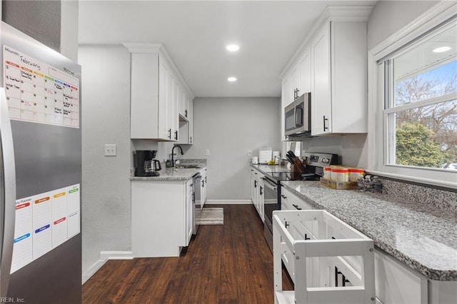 kitchen with white cabinetry, sink, stainless steel appliances, and light stone countertops