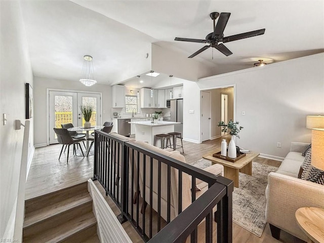 living room with lofted ceiling, sink, light hardwood / wood-style floors, and french doors