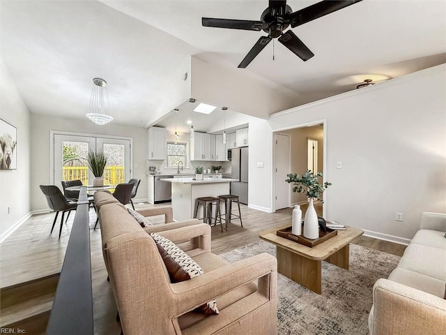 living room featuring ceiling fan, vaulted ceiling, and light hardwood / wood-style flooring