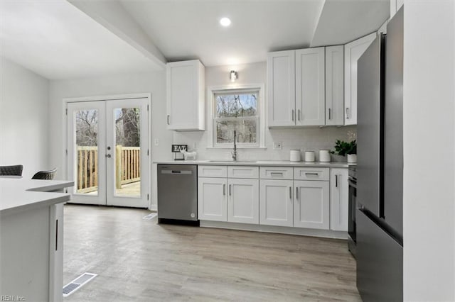 kitchen featuring sink, dishwasher, white cabinetry, backsplash, and french doors