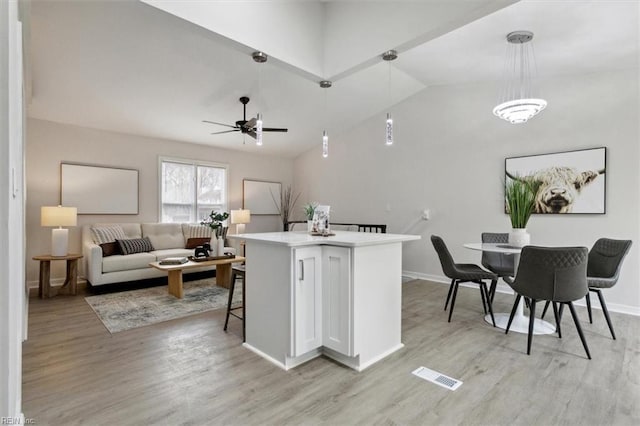 kitchen featuring lofted ceiling, light hardwood / wood-style flooring, hanging light fixtures, a kitchen breakfast bar, and a center island