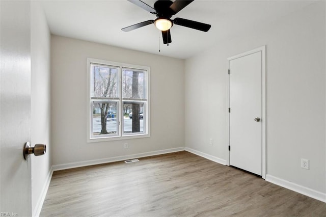 empty room with ceiling fan and light hardwood / wood-style flooring