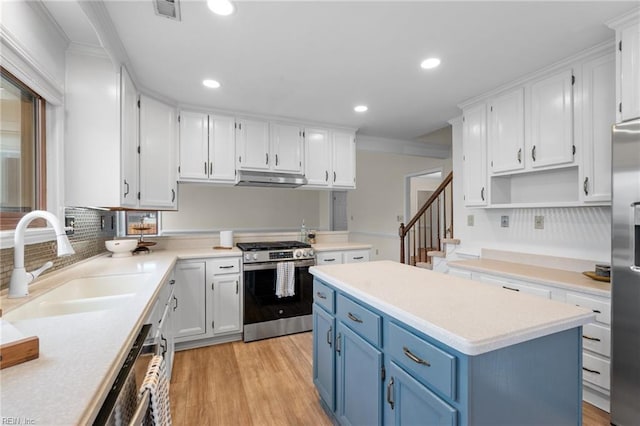 kitchen with blue cabinets, white cabinetry, sink, a center island, and stainless steel appliances