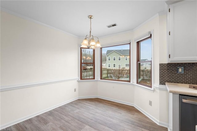 unfurnished dining area featuring crown molding, light hardwood / wood-style floors, and a chandelier