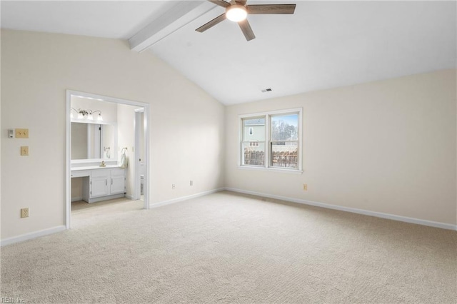 unfurnished bedroom with light carpet, vaulted ceiling with beams, and ensuite bathroom