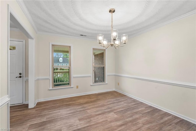 unfurnished room featuring an inviting chandelier, hardwood / wood-style flooring, and ornamental molding