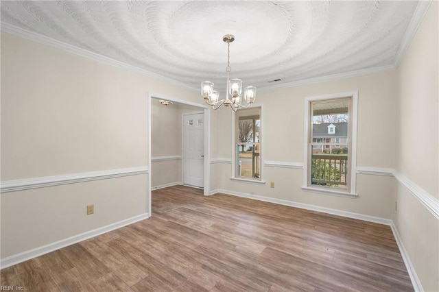 unfurnished dining area with an inviting chandelier, ornamental molding, and hardwood / wood-style floors