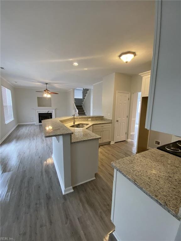 kitchen featuring sink, dark wood-type flooring, a breakfast bar, white cabinetry, and light stone countertops