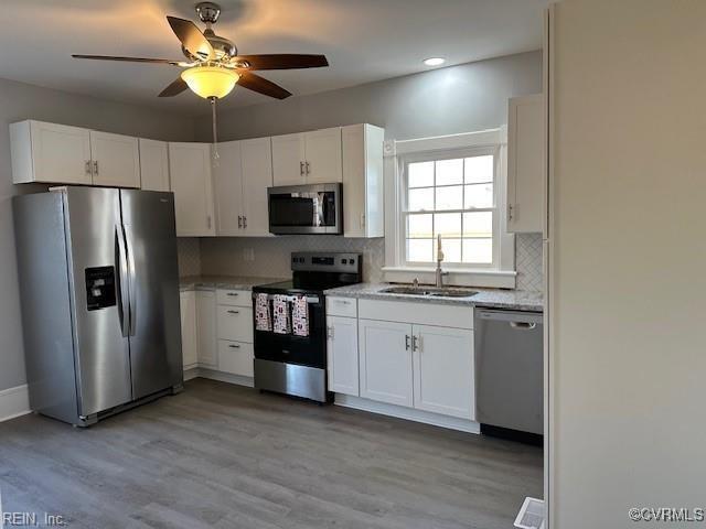 kitchen featuring stainless steel appliances, white cabinetry, sink, and backsplash