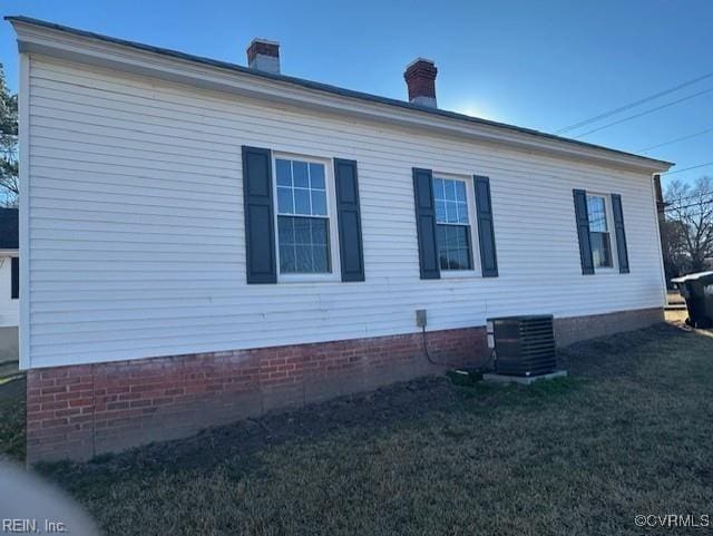 view of side of home featuring a yard and central AC