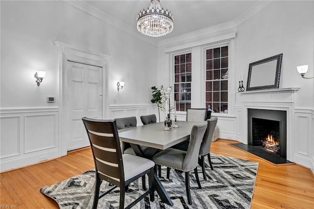 dining area with crown molding, a chandelier, and light wood-type flooring