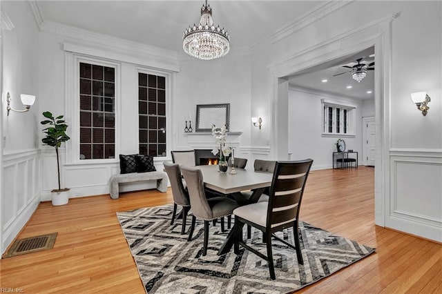 dining area featuring ceiling fan with notable chandelier, ornamental molding, and hardwood / wood-style floors