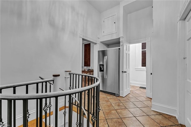 hallway featuring a towering ceiling and light tile patterned floors