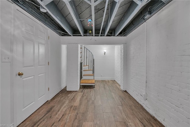 basement featuring wood-type flooring and brick wall