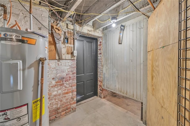 basement featuring brick wall and electric water heater