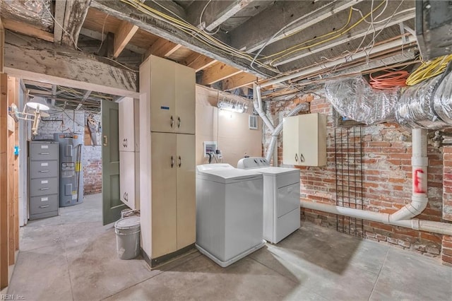 basement with washing machine and dryer, electric water heater, and brick wall