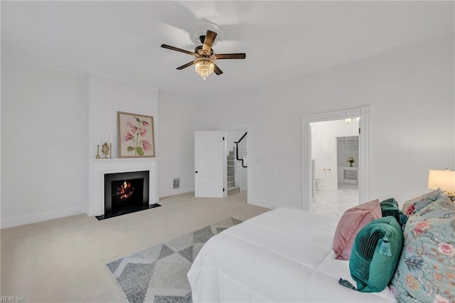 bedroom featuring light carpet, ensuite bath, and ceiling fan