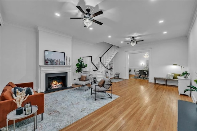 living room with hardwood / wood-style flooring, ceiling fan, and ornamental molding