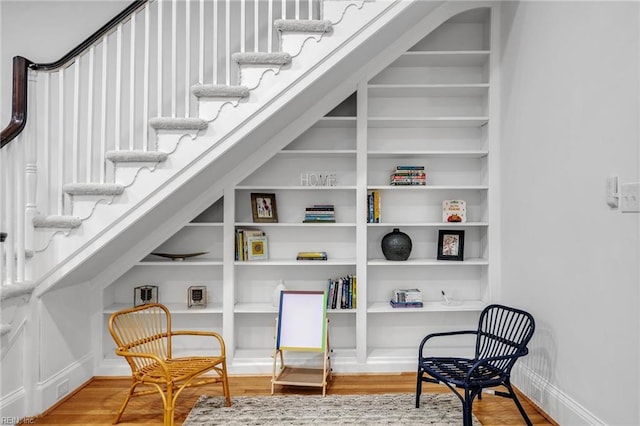 sitting room featuring hardwood / wood-style flooring and built in shelves