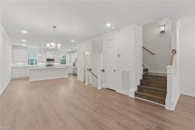 unfurnished living room with ornamental molding, a chandelier, and light hardwood / wood-style floors