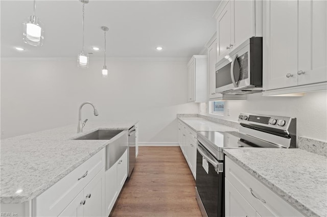 kitchen featuring sink, appliances with stainless steel finishes, pendant lighting, a kitchen island with sink, and white cabinets