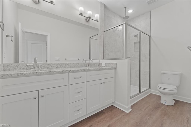 bathroom with vanity, hardwood / wood-style flooring, a shower with door, and toilet